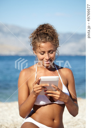 Woman with an e-reader on vacation at the beach 49766677