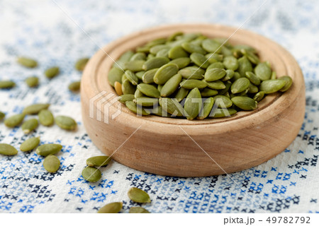 Peeled pumpkin seeds in wood bowl Peeled pumpkin seeds in wood bowl 49782792