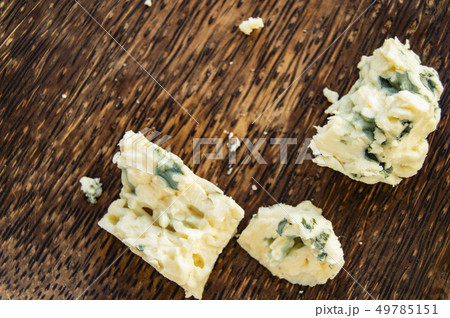 Three broken pieces of blue cheese on a dark wooden plate and minimalism, top view, copy space 49785151