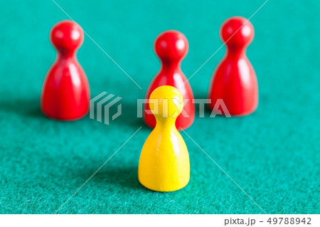 yellow pawn in front of three red pawns on green 49788942