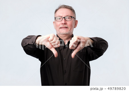Senior man in black shirt showing thumb down gesture Senior man in black shirt showing thumb down gesture 49789820