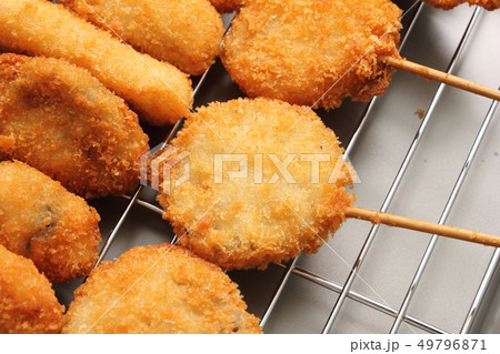 揚げバットにのせられた多数の串揚げ(串カツ)。 49796871