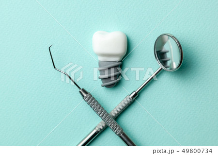 White teeth implants on green mint background and dentist tools mirror, hook. 49800734