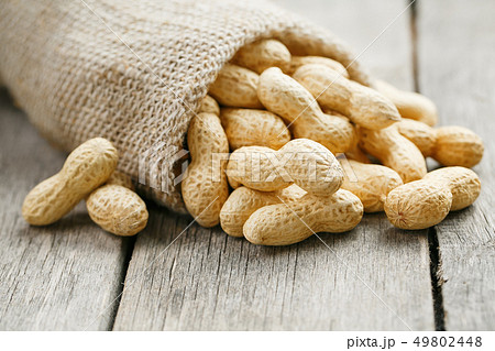 Peanuts in a miniature burlap bag on old, gray Peanuts in a miniature burlap bag on old, gray 49802448