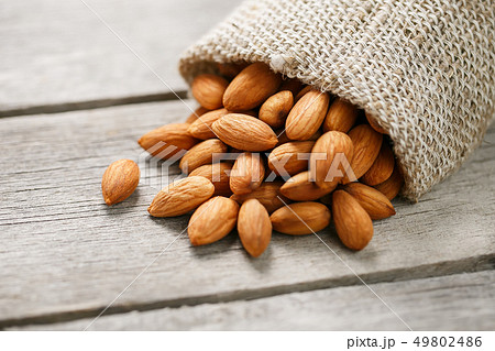 Almond nuts in a burlap bag on a wooden gray 49802486