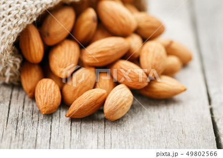 Almond nuts in a burlap bag on a wooden gray 49802566