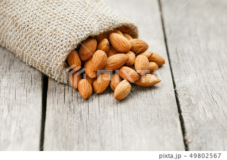 Almond nuts in a burlap bag on a wooden gray 49802567
