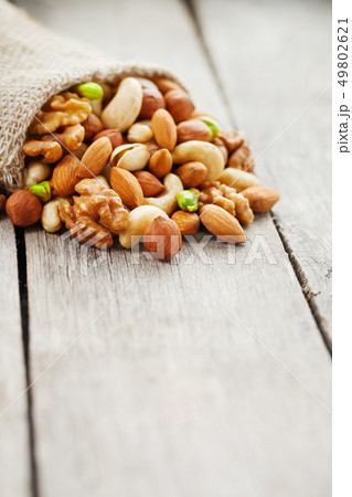 Mix of different nuts in a wooden cup against the 49802621