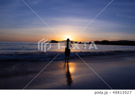 海に沈む夕焼け 鹿児島県脇本海水浴場の夕焼け 夕日を見る女性の写真素材