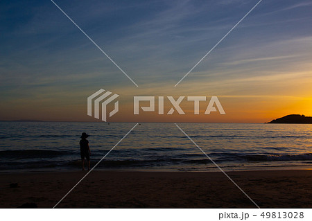 海に沈む夕焼け　鹿児島県脇本海水浴場の夕焼け　夕日を見る女性 49813028