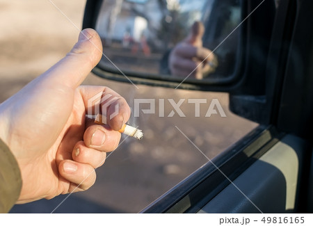 people hand holding a cigarette in a car people hand holding a cigarette in a car 49816165
