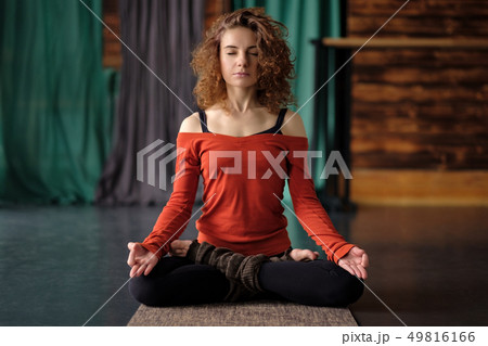 Yoga girl sitting in Lotus pose or Padmasana. Practicing on mat Yoga girl sitting in Lotus pose or Padmasana. Practicing on mat 49816166