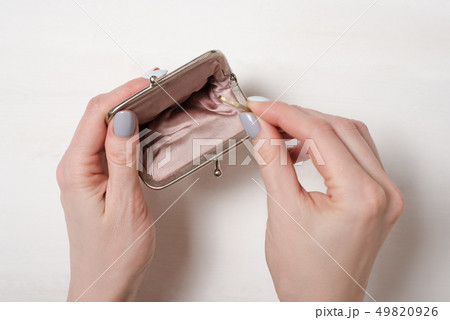 Hand puts a coin in an empty open metal purse on a 49820926