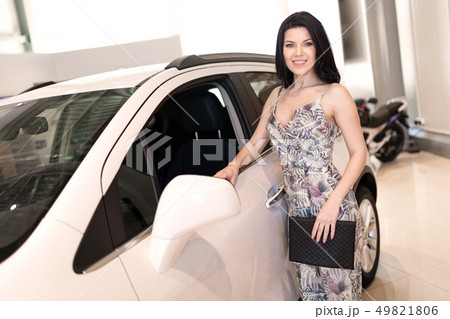 Beautiful fashionable brunet look at her new car in dealership showroom 49821806
