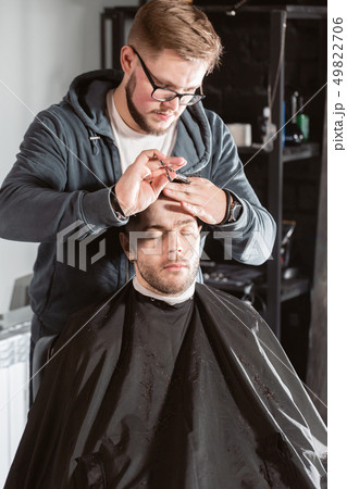 Hair cutting with metal scissors. Master cuts hair and beard of men in the barbershop, hairdresser 49822706