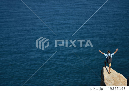 Traveler posing on stone on rocky seashore outdoors Traveler posing on stone on rocky seashore outdoors 49825143