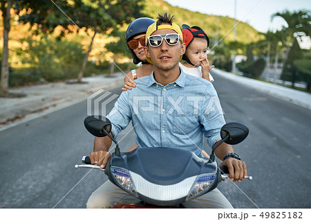 Parents with their little kid riding motorcycle on sunny city street Parents with their little kid riding motorcycle on sunny city street 49825182