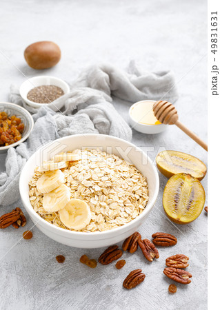Oat flakes with fruits, nuts and honey in bowl Oat flakes with fruits, nuts and honey in bowl 49831631