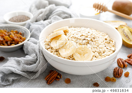 Oat flakes with fruits, nuts and honey in bowl Oat flakes with fruits, nuts and honey in bowl 49831634