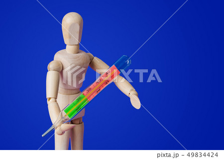 Wooden toy figure with thermometer on blue Wooden toy figure with thermometer on blue 49834424