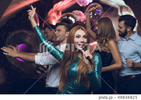woman in a green dress is singing with her friends woman in a green dress is singing with her friends 49836825