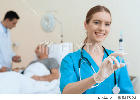 man lies on a cot. Doctor and a nurse help him. 49838003