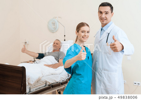 man lies on a cot. Doctor and a nurse help him. 49838006