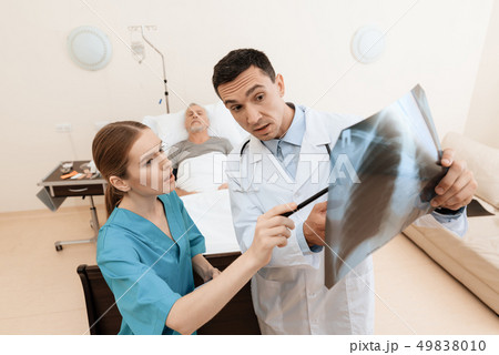 man lies on a cot. Doctor and a nurse help him. 49838010