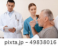 man lies on a cot. Doctor and a nurse help him. 49838016