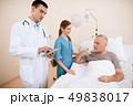 man lies on a cot. Doctor and a nurse help him. 49838017