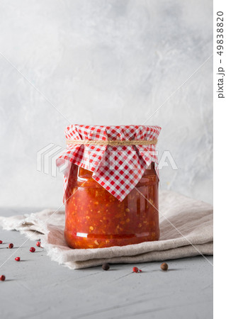 Vegetable sauce adjika with tomatoes, garlic, bell peppers in jar on light background. Vegetable sauce adjika with tomatoes, garlic, bell peppers in jar on light background. 49838820