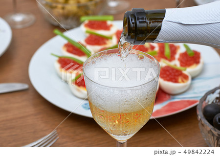Pouring champagne into the glass from the bottle, 49842224