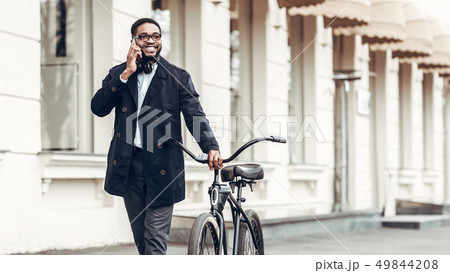 African-american businessman talking on phone, riding bicycle African-american businessman talking on phone, riding bicycle 49844208