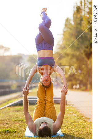 Couple of young man and woman practicing acro yoga Couple of young man and woman practicing acro yoga 49845700