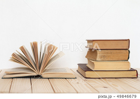 An open book next to a stack of vintage books on a An open book next to a stack of vintage books on a 49846679