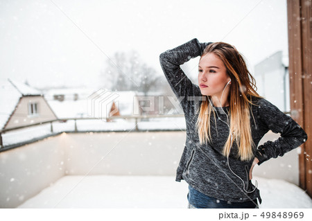 A portrait of young girl or woman with earphones outdoors in winter. A portrait of young girl or woman with earphones outdoors in winter. 49848969