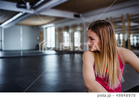 A portrait of young sad and frustrated girl or woman sitting in a gym. 49848970