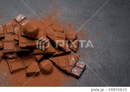 Dark or milk organic chocolate pieces, cocoa powder and truffle candies on dark concrete backgound 49850810