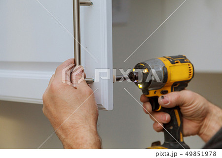 The worker installing handle the white cabinet 49851978