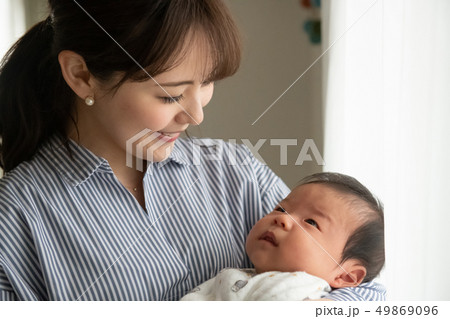 赤ちゃんを抱く若い母親 笑顔 日本人親子の写真素材