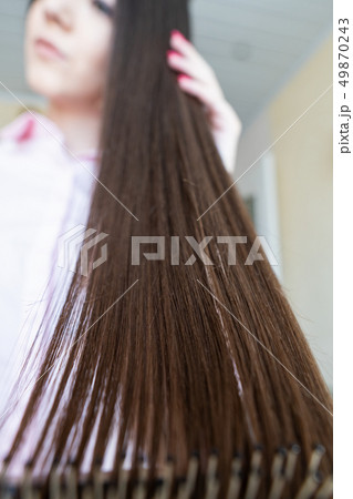 Brunette girl in a pink shirt is combing her beautiful long hair comb 49870243