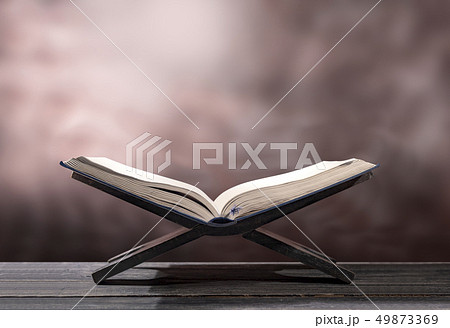 Quran open in wooden placemat on wooden table Quran open in wooden placemat on wooden table 49873369