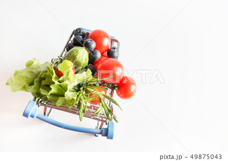 Grocery trolley with tomatoes on blue. Space for text. 49875043