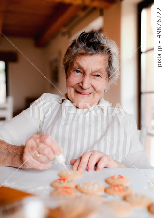 Elderly woman making and decorating cakes in a kitchen at home. 49876222