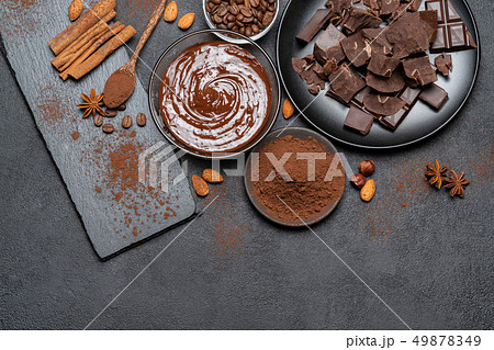 Melted chocolate or Hazelnut spread in glass bowl and chocolate pieces on dark concrete background 49878349