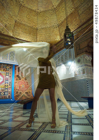 Beautiful Moroccan Girl in short golden dress and white mantle cloak in Rich interior of Picturesque 49878434