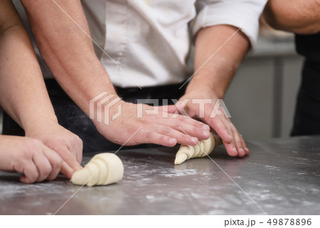 Pastry Chef rolling fresh raw croissant dough. Pastry Chef rolling fresh raw croissant dough. 49878896
