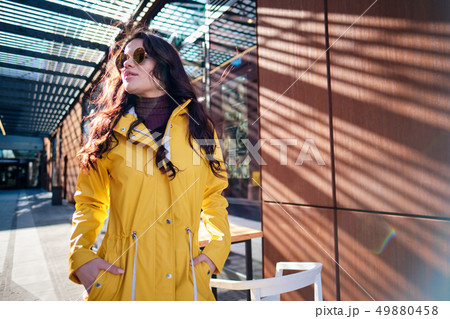 young woman in yellow raincoat at city street young woman in yellow raincoat at city street 49880458