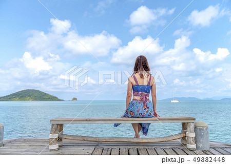 Woman sitting on a chair on the bridge in the sea 49882448