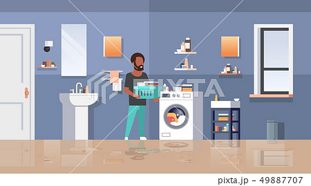 man with clothes basket standing near washing machine african american guy doing housework laundry 49887707